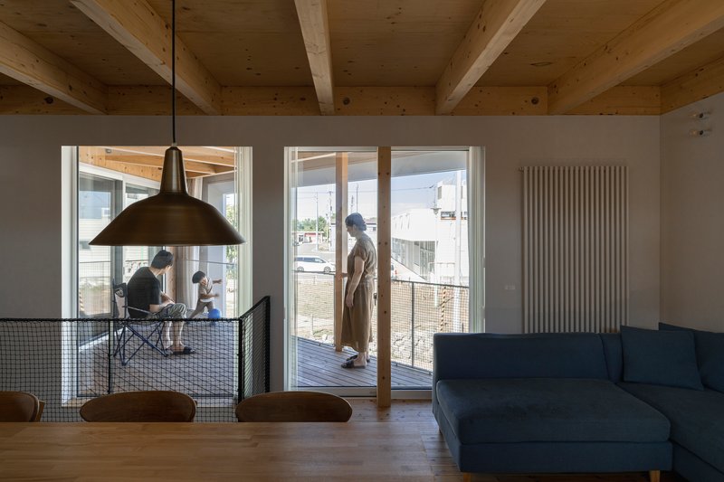 Living space with glass doors opening to the timber deck and family gathered at the dining table