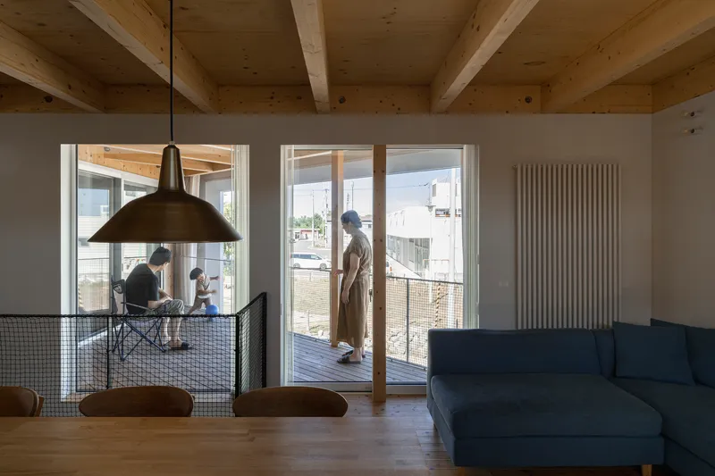 Living space with glass doors opening to the timber deck and family gathered at the dining table