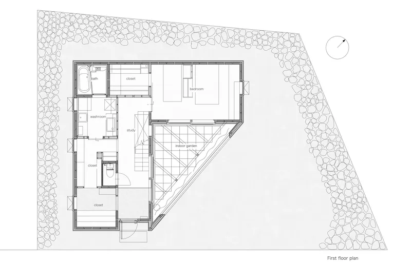 First floor plan drawing showing an angular residence with triangular courtyard and gravel perimeter landscaping