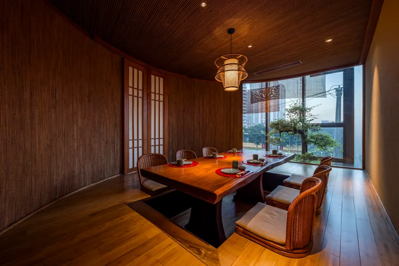 Private dining room with slatted timber ceiling and woven pendant light overlooking a courtyard tree
