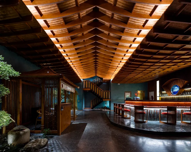 Double-height lobby showing the vaulted wood-slat ceiling with integrated lighting above a central interior garden