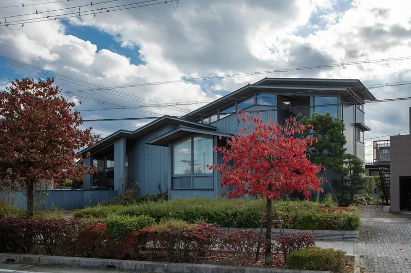 Street view of corrugated metal facade with clerestory windows under autumn foliage and overhead power lines