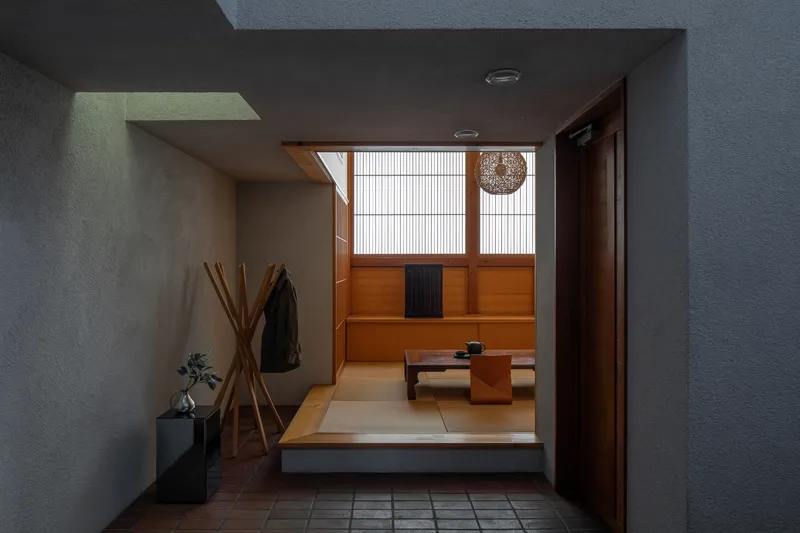 View from entry vestibule through open doorway into tatami room with low table and pendant light