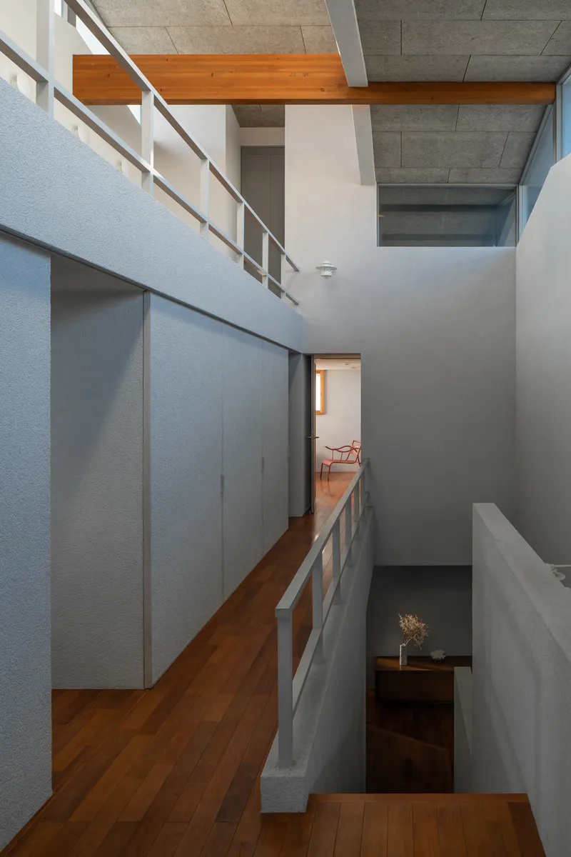 Three-level void with timber walkway, metal railing and exposed concrete ceiling beams