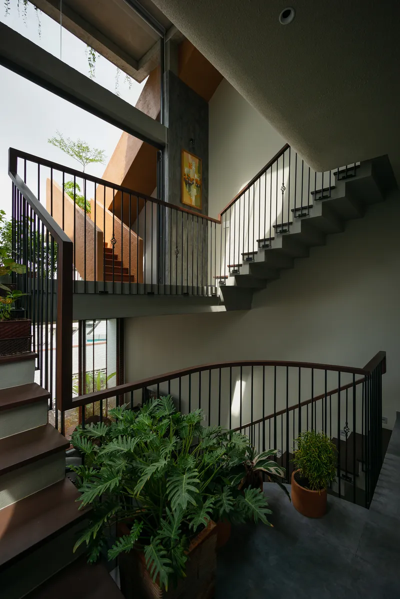 Interior stairwell with black steel railings and potted ferns under skylights and clerestory glazing