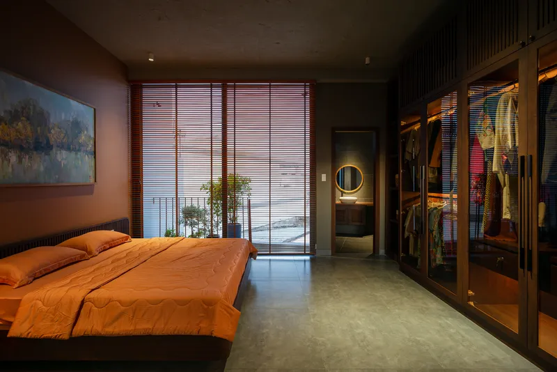 Bedroom view toward open closet and adjoining bathroom with circular mirror at twilight