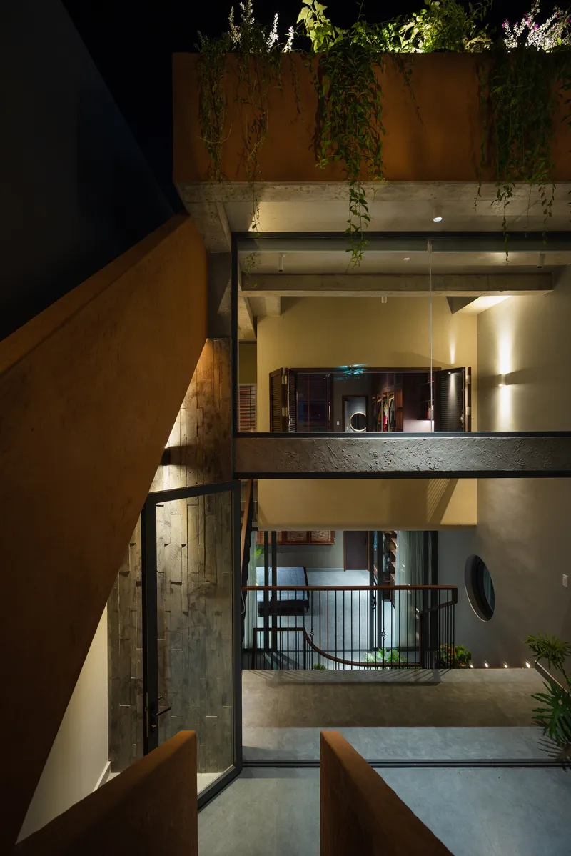 Nighttime view through a multilevel courtyard with concrete balconies and cascading vegetation above