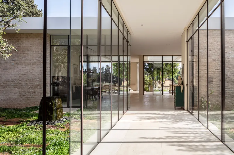 Glass-walled corridor connecting interior spaces with views to planted courtyard on one side