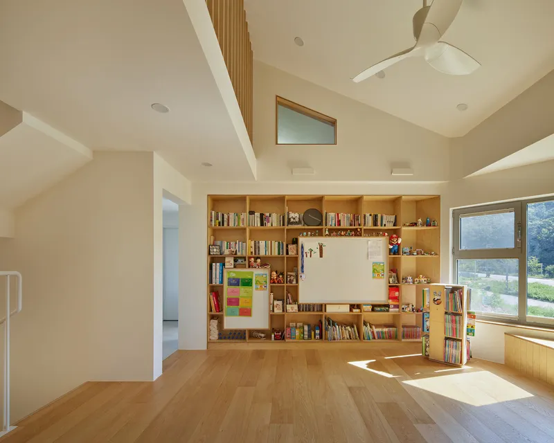 Open room with built-in timber shelving wall and whiteboard under a sloped ceiling with clerestory windows