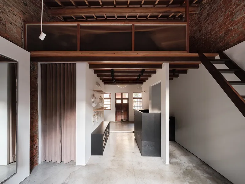Double-height space with mezzanine stair, exposed brick walls, and timber ceiling structure with clerestory windows