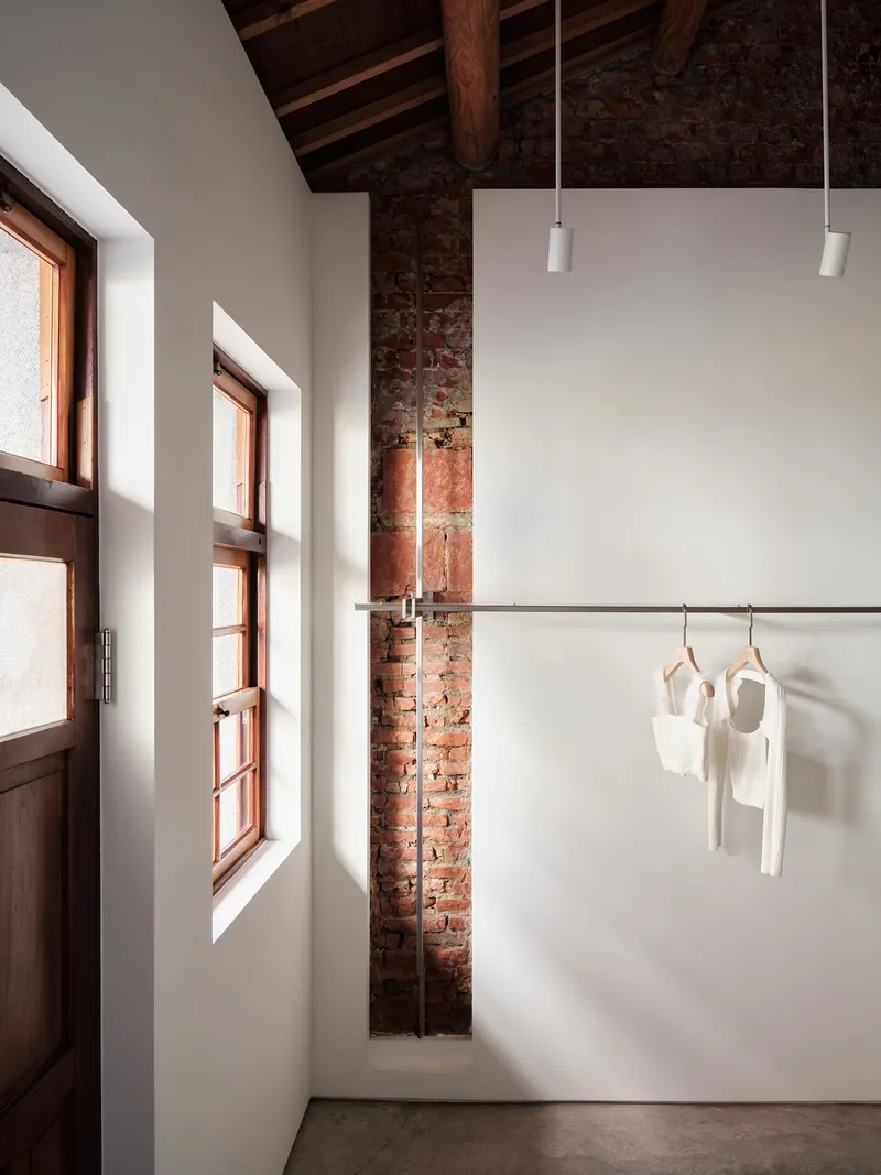 Deep window reveals framing sunlight beside the exposed brick column in the entry
