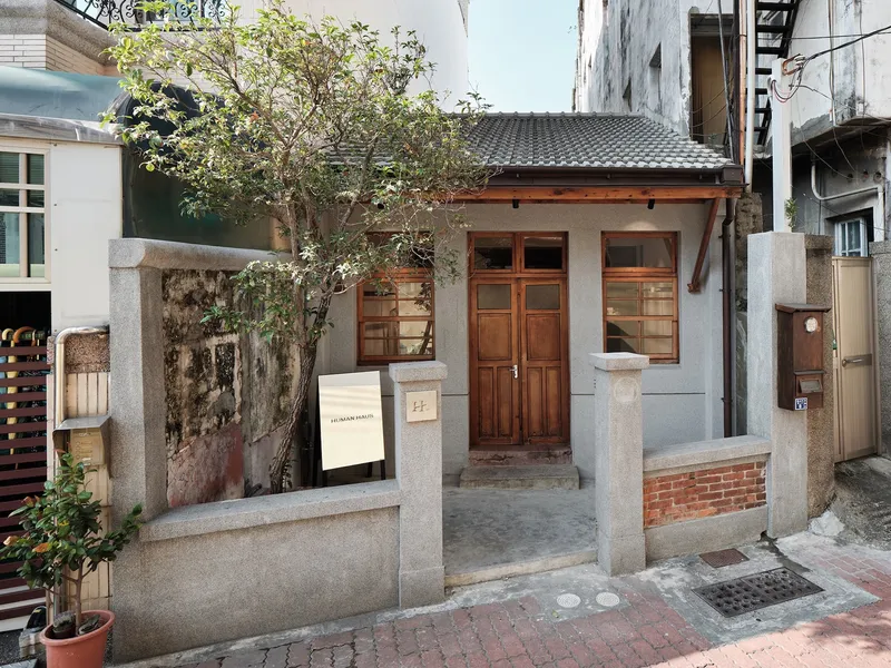 Street view of the low-scale timber and concrete shopfront with tiled roof and climbing vines