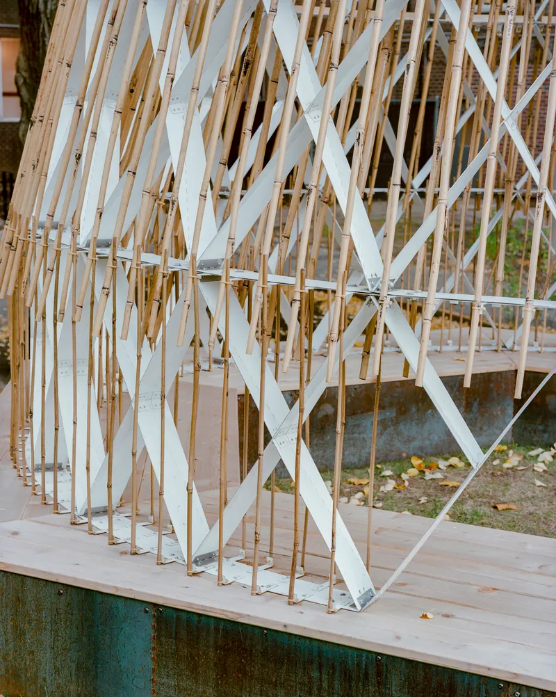 Corner detail of bamboo screen with white diagonal supports anchored on timber deck