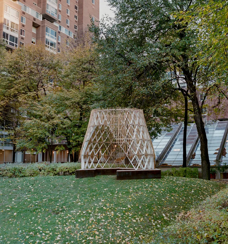 Tapered timber structure elevated on weathered steel beams among mature trees in autumn