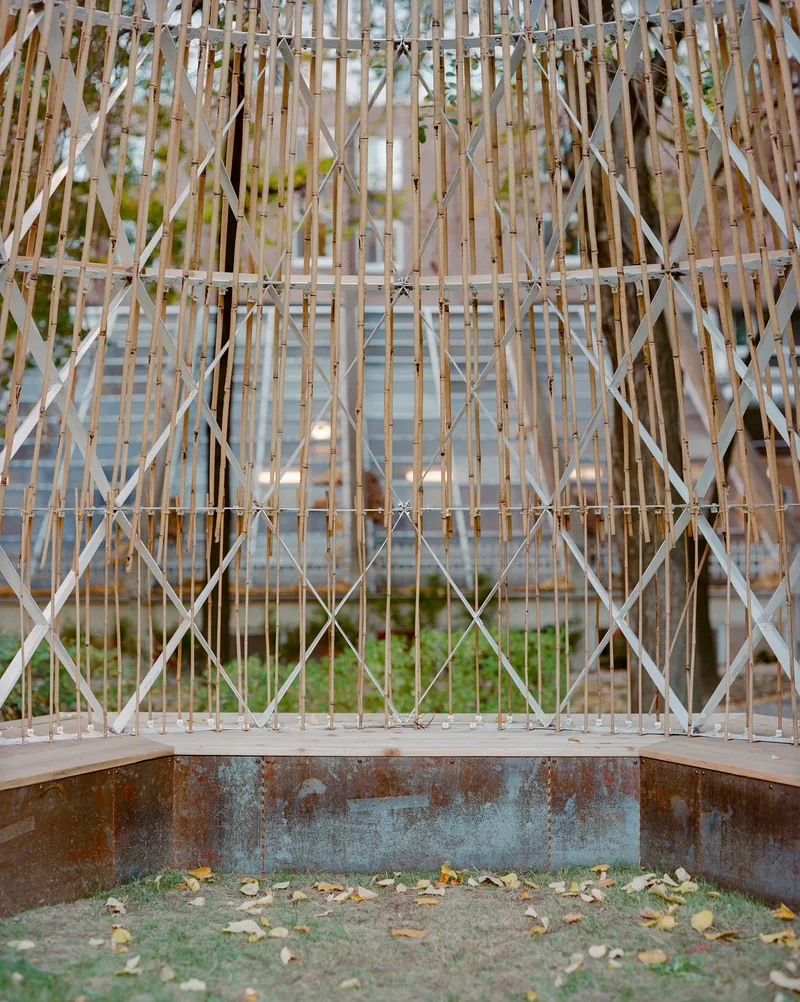 Close-up of the lattice screen base showing diagonal timber bracing and weathered steel plinth
