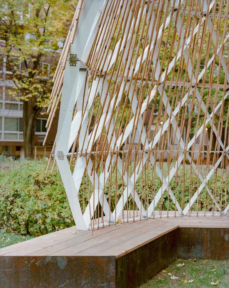 Detail of the angled lattice wall meeting the timber bench and rusted steel base