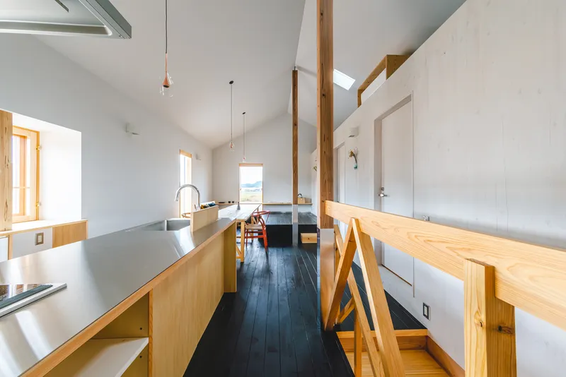 Kitchen island with grey countertop and exposed timber posts dividing the white-walled interior