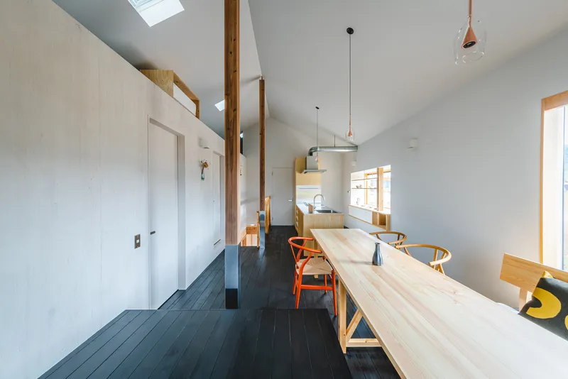 Dining space with vaulted ceiling and skylights running along dark timber floorboards