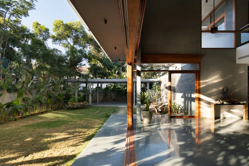 Corner veranda with timber columns and concrete soffit opening onto lawn and trees in morning sun