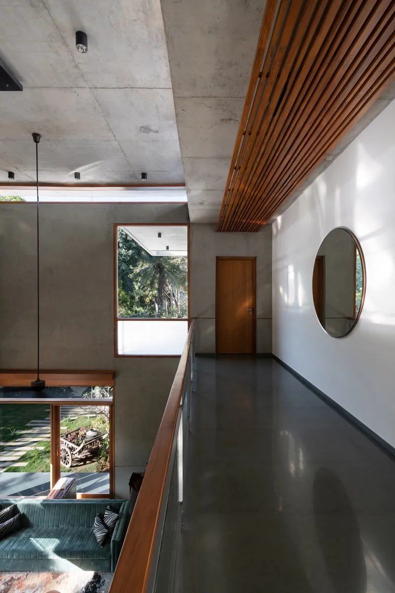 Upper corridor with timber slatted ceiling panel and exposed concrete soffit overlooking double-height space below
