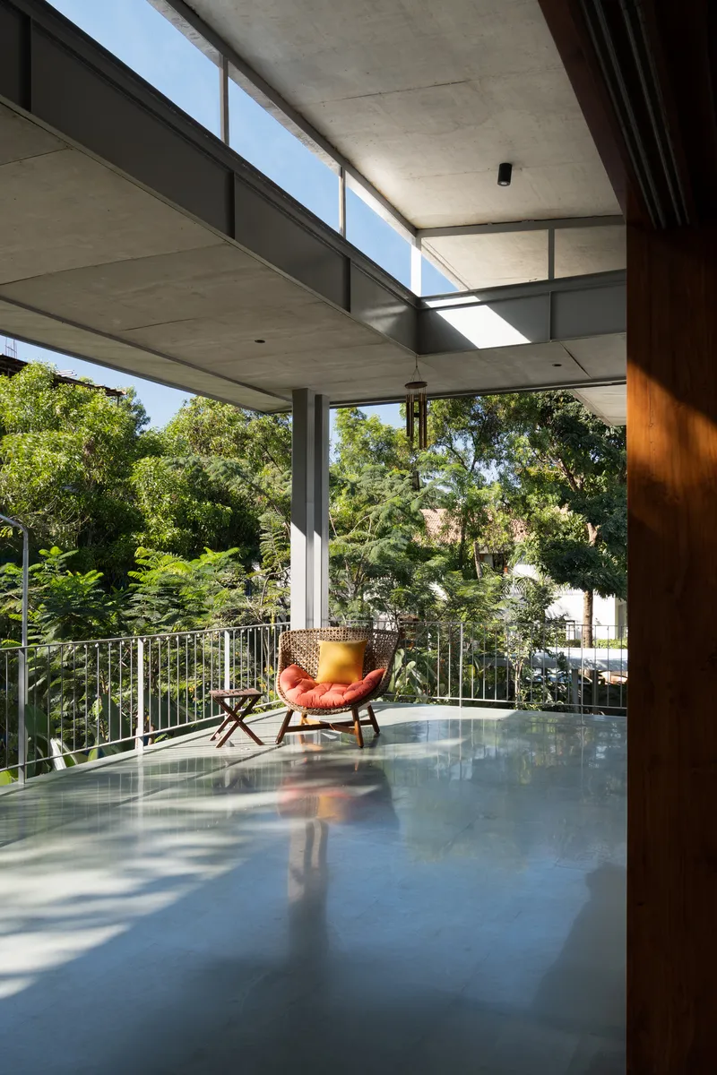Covered balcony with polished concrete floor and an orange leather chair facing dense green trees