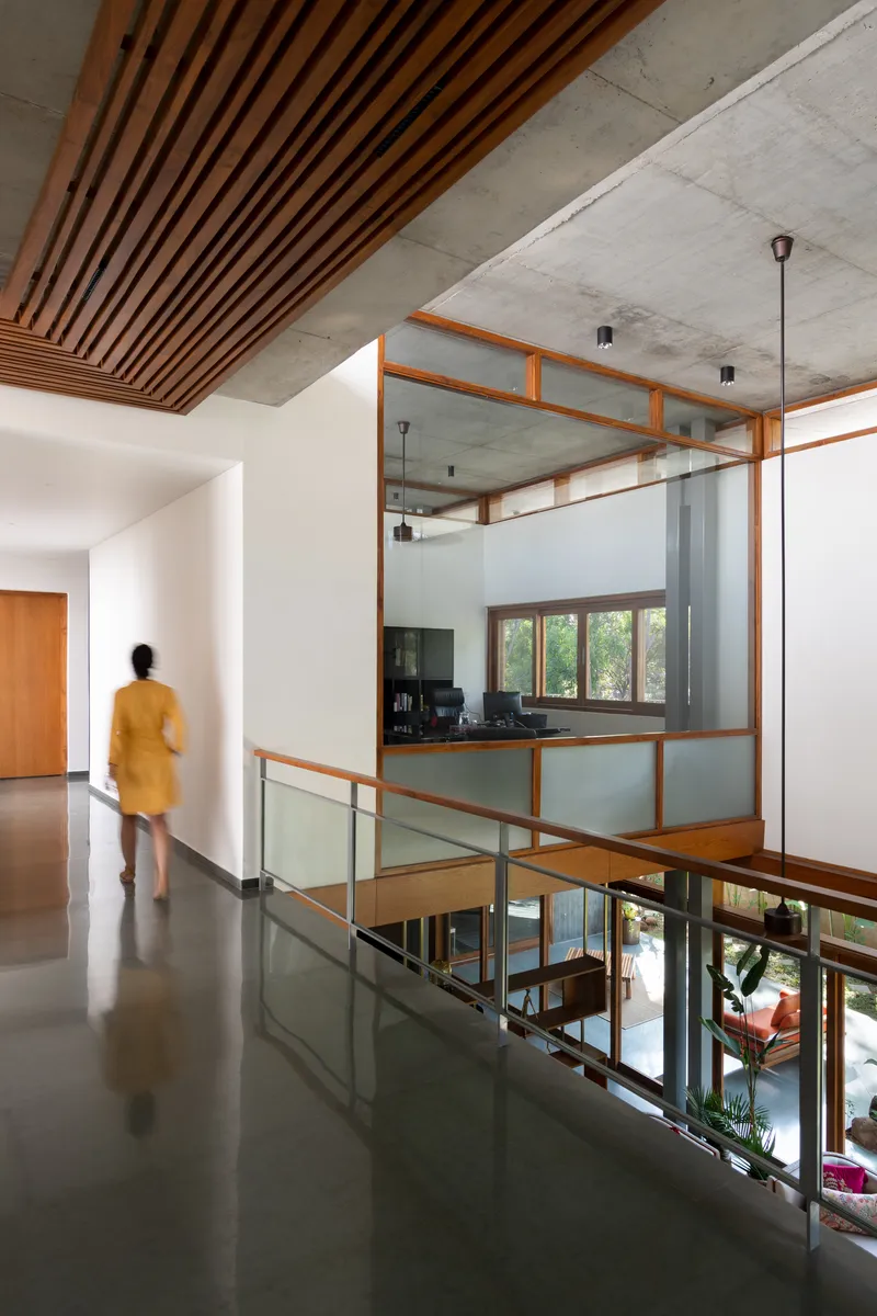 Upper level hallway with timber slat ceiling and glass-railed opening overlooking the double-height space below