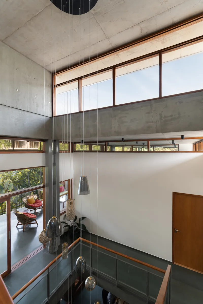 Double-height void with pendant lights descending through the space framed by timber-trimmed clerestory windows