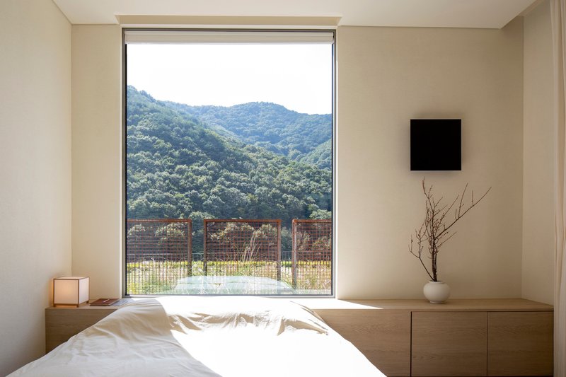 Bedroom with picture window framing mountain view and wire mesh balcony railing below
