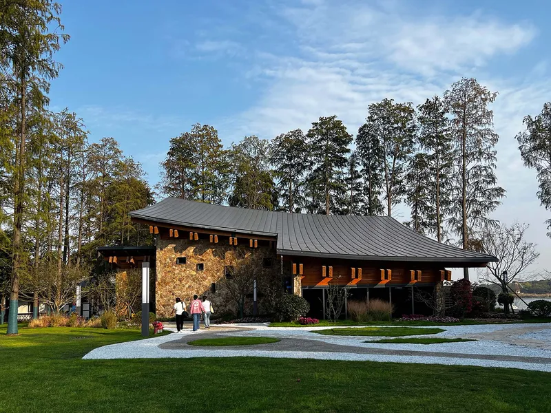 Gravel courtyard approach showing the metal roofs and stone walls with visitors walking toward the entrance under afternoon light
