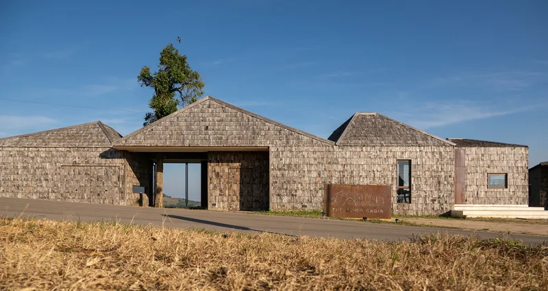 Front elevation showing clustered gabled volumes clad in textured stone with a tree emerging from one roof