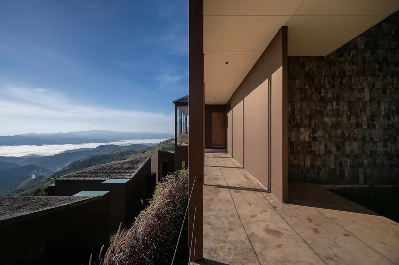 Covered walkway with concrete floor and weathered wood cladding overlooking mountains and low clouds