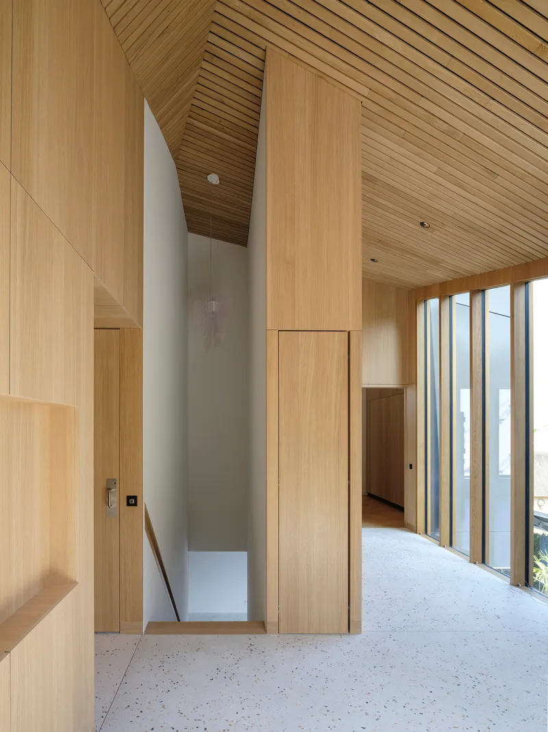Interior hallway with timber-clad walls and slat ceiling overlooking a double-height void