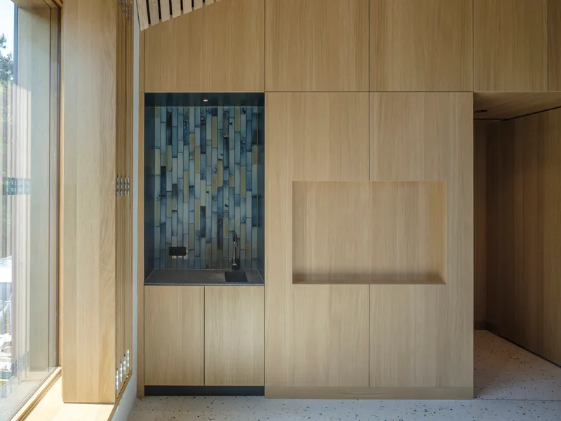 Built-in cabinetry with blue tile backsplash niche set within light wood paneling