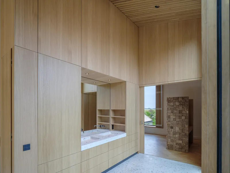 Timber-lined passage connecting to a living space with brick chimney and terrazzo flooring