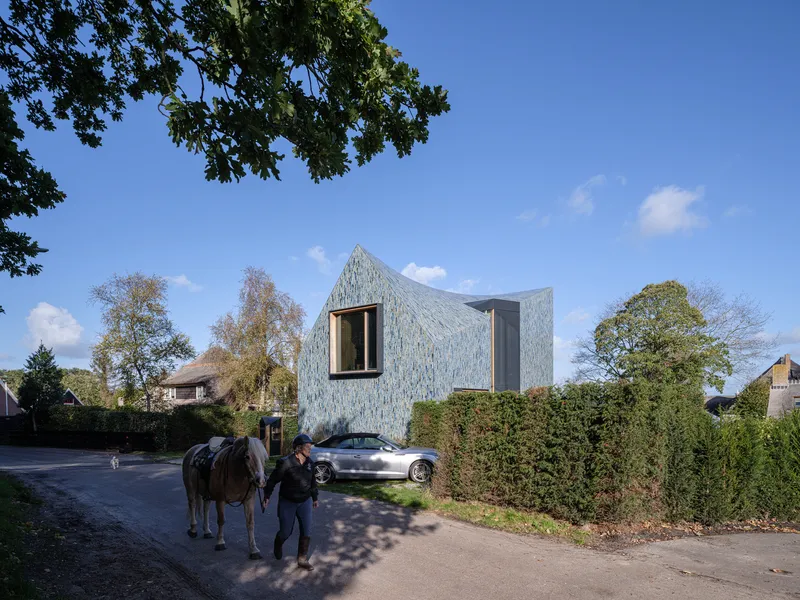 Person with horse passing the tile-clad facade along the residential street in autumn