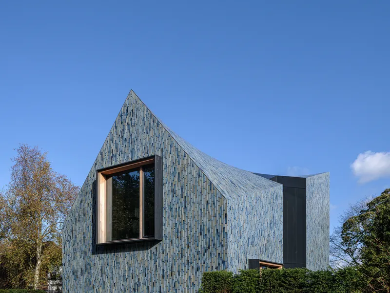 Gabled facade showing the glazed ceramic tile cladding and projecting window frame against blue sky
