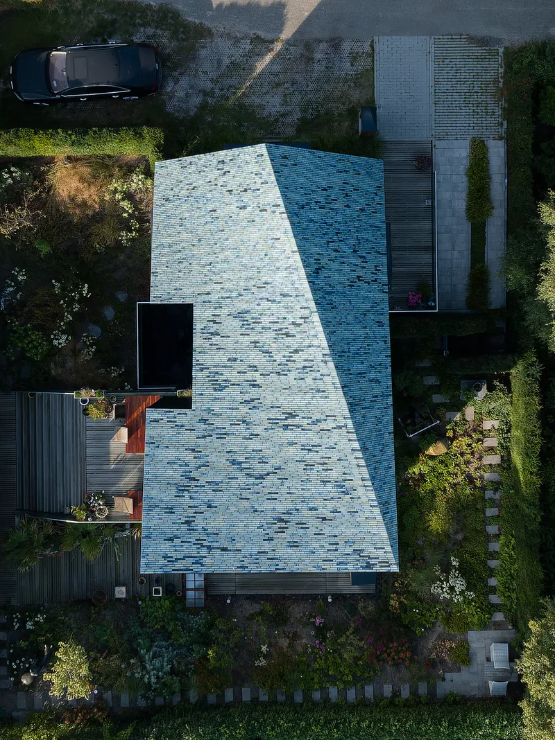 Top-down view of the variegated blue tile roof with stepping stones crossing the planted garden below