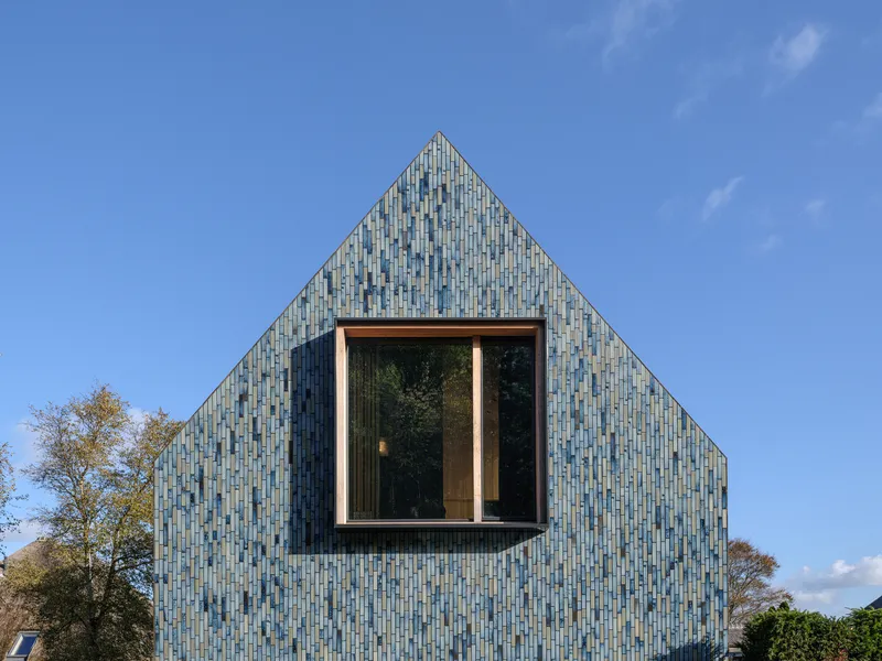 Gable end with central bay window framed in wood against the patterned blue tile cladding