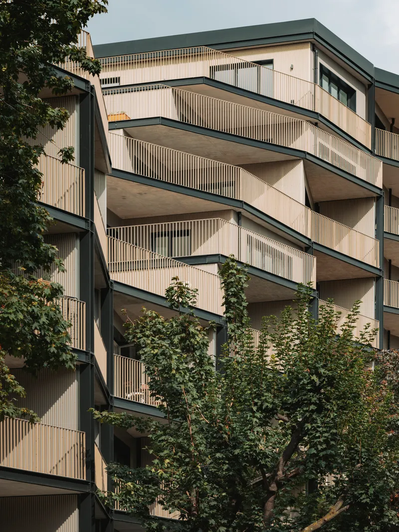 Close-up of the cantilevered balconies with vertical timber screening and trees in the foreground