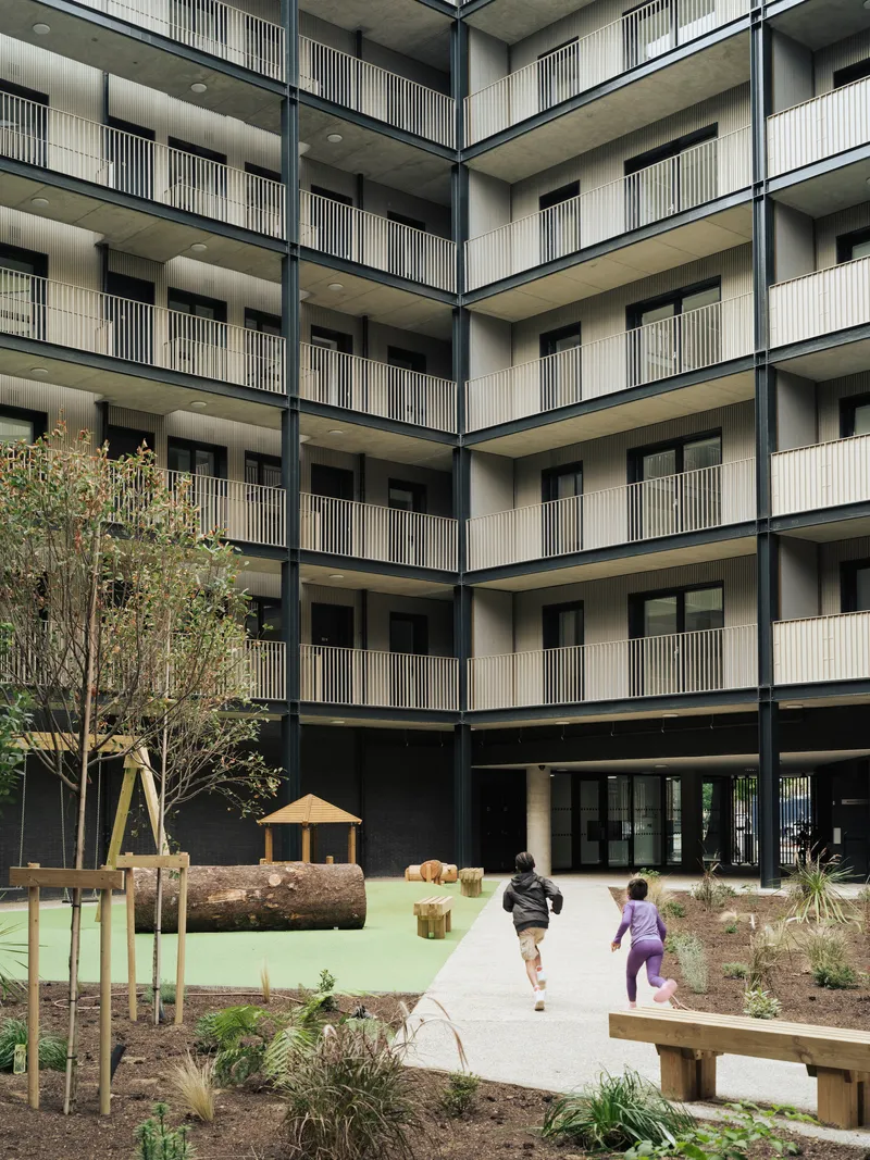 Interior courtyard with timber play structures and planted beds where two children are running