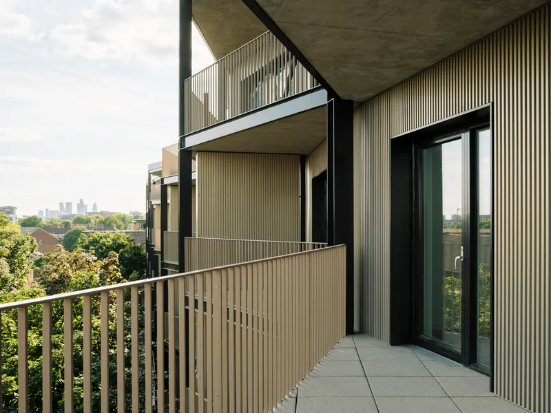 Balcony terrace with vertical metal railings and glazed sliding doors opening to an interior space