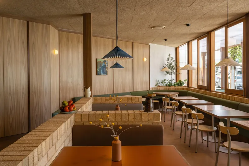 Interior dining area with pale brick banquette seating and vertical timber paneling under a cork ceiling