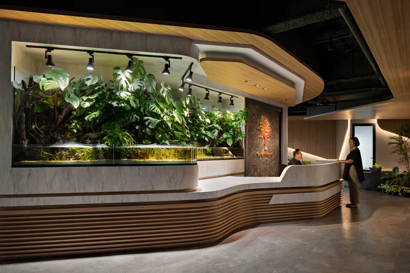 Reception desk with living green wall and track lighting as a figure approaches the counter
