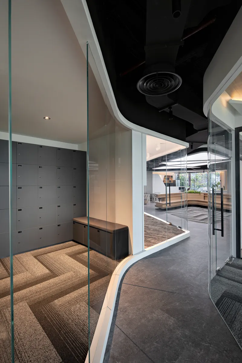 Glass door entry to locker room with curved soffit and exposed black ceiling ducts