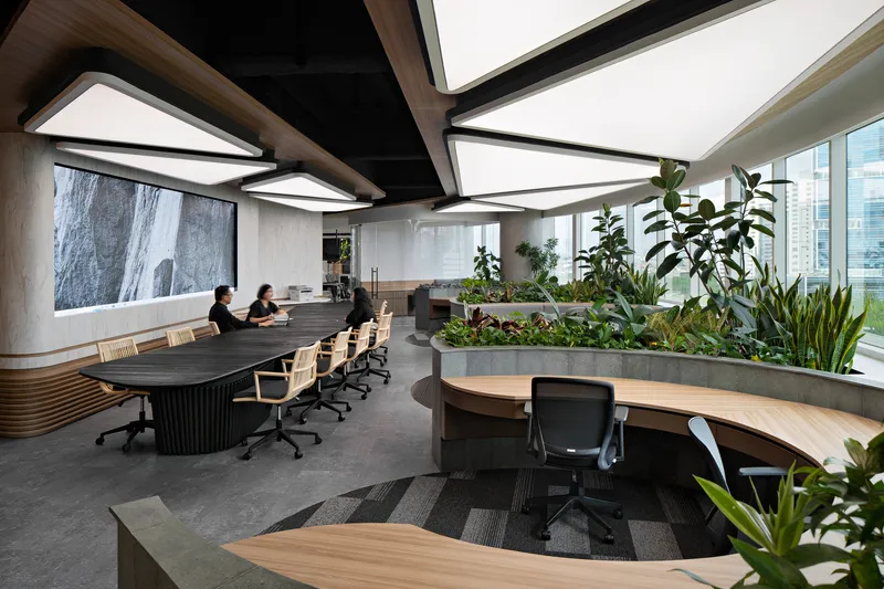 Office space with triangular ceiling light panels, planted concrete planter boxes and curved workstations