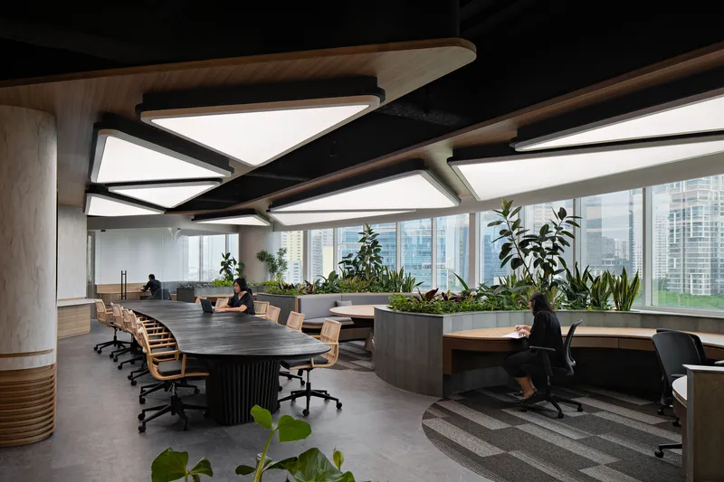 Open workspace showing tiered carpeted platforms leading to curved desks beneath geometric skylights