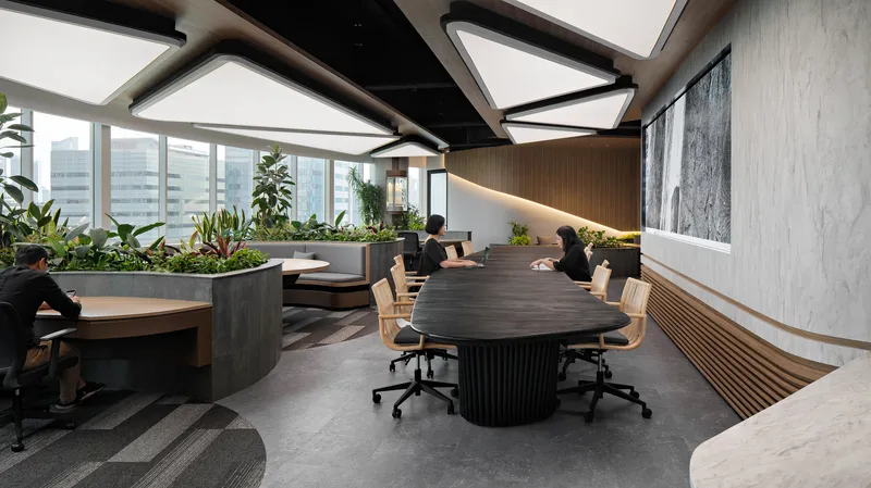 Conference table with fluted black base surrounded by planted beds and timber-clad walls