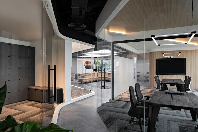 Glass-enclosed meeting rooms with exposed ceiling and locker wall visible through transparent partitions