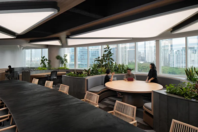 Office workspace with planted divider boxes, floor-to-ceiling windows, and curved banquette seating overlooking the skyline