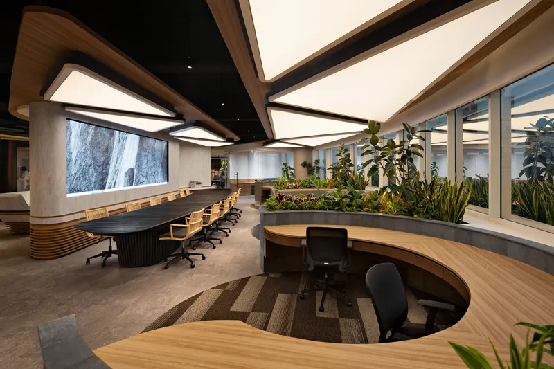Conference area with elongated table and circular workstations set within terraced carpet zones and integrated planters